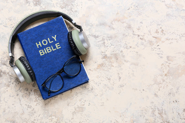 Holy Bible, eyeglasses and modern headphones on light background - 写真・画像