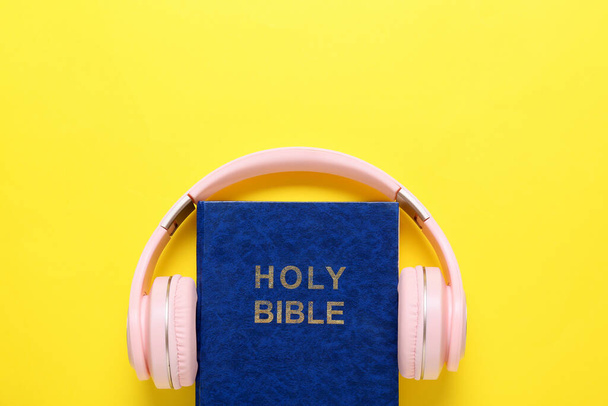 Священна Біблія і сучасні навушники на кольоровому фоні
 - Фото, зображення