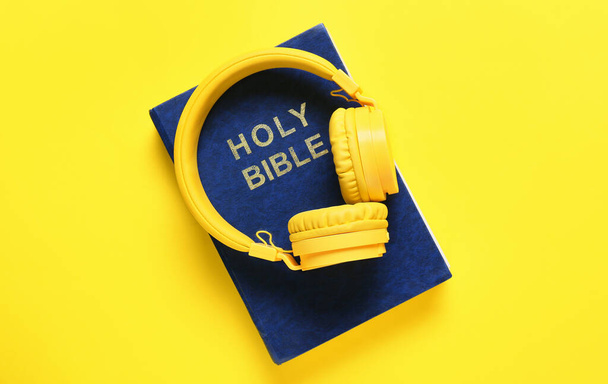 Santa Biblia y auriculares modernos sobre fondo de color - Foto, imagen