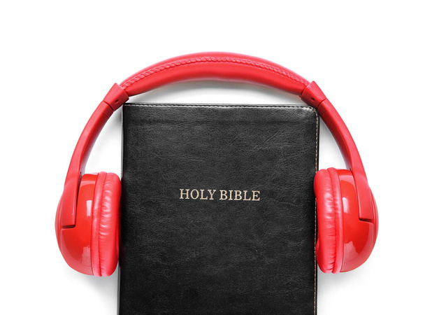 Santa Biblia y auriculares modernos sobre fondo blanco - Foto, imagen
