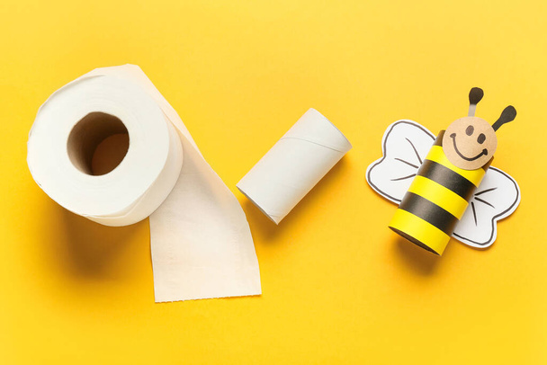 Пчела из картона, рулон туалетной бумаги и пустая трубка на желтом фоне - Фото, изображение