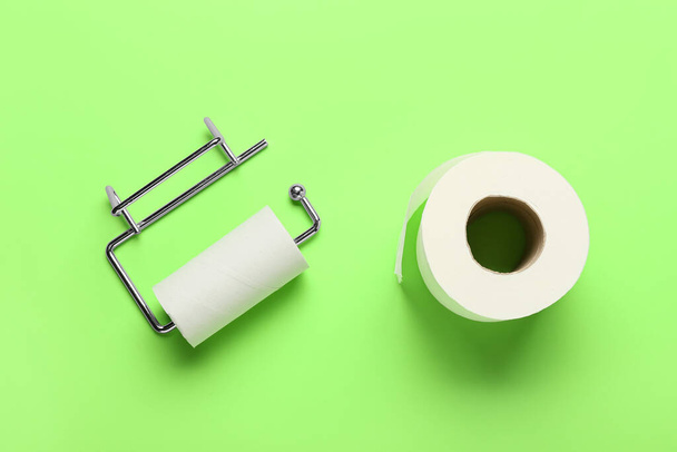 Holder with cardboard tube and toilet paper roll on green background - Photo, Image