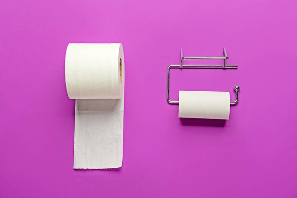 Uchwyt z tekturową rurką i rolką papieru toaletowego na fioletowym tle - Zdjęcie, obraz