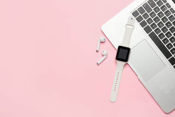 Розумний годинник, навушники та ноутбук на рожевому фоні
 - Фото, зображення