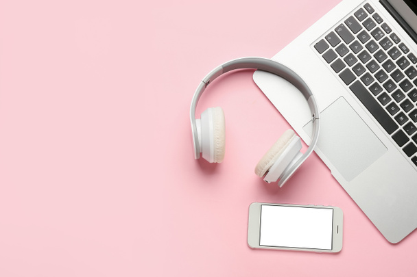 Modern headphones, mobile phone and laptop on pink background - Foto, Imagen