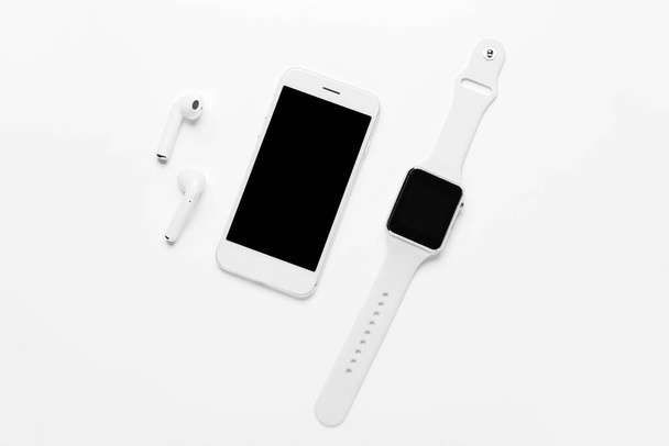 Moderne koptelefoon, mobiele telefoon en smart watch op witte achtergrond - Foto, afbeelding