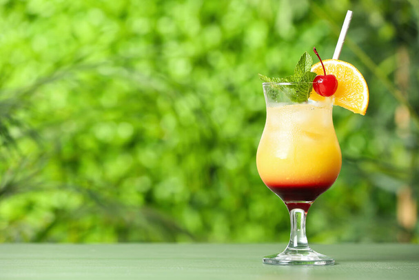 Glass of tasty Tequila Sunrise cocktail on table outdoors - Zdjęcie, obraz