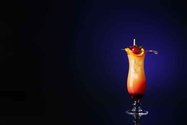 Vaso de sabroso cóctel Tequila Sunrise sobre fondo de color oscuro - Foto, imagen