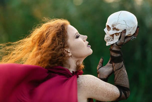Young witch with skull outdoors - Zdjęcie, obraz