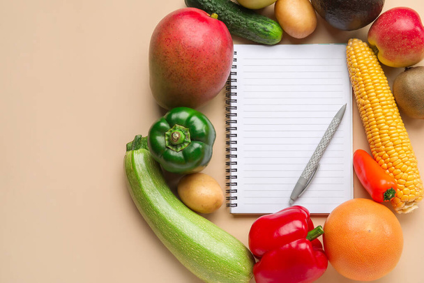 空のノート、ペン、果物や野菜の色を背景に。ビーガンデー - 写真・画像