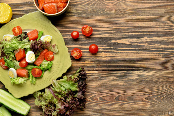 Insalata saporita con salmone e verdure fresche in piatto su fondo di legno - Foto, immagini