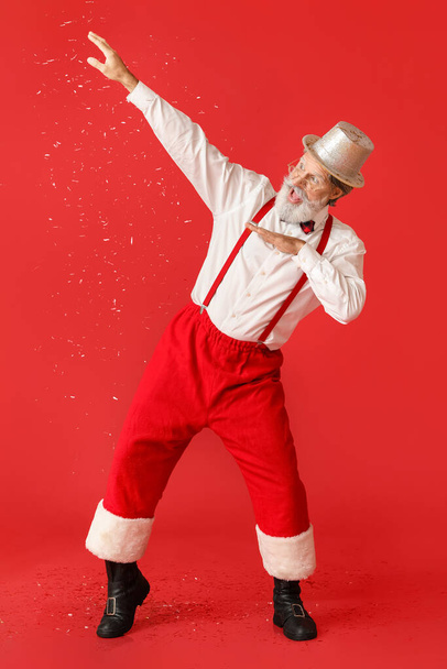 Dancing Santa Claus and falling confetti on color background - Zdjęcie, obraz