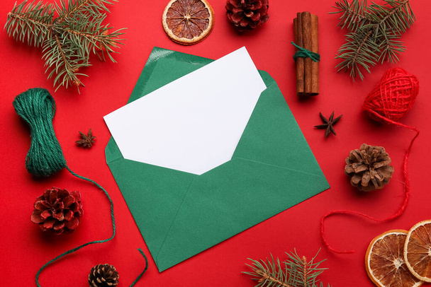 Hermosa composición navideña con tarjeta en blanco y sobre sobre fondo rojo, primer plano - Foto, imagen