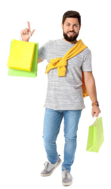 Handsome man with Black Friday shopping bags pointing at something on white background - Foto, immagini