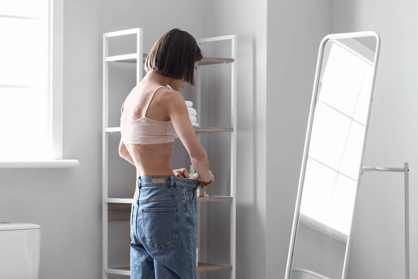 Young skinny woman in front of mirror at home. Anorexia concept - Photo, Image