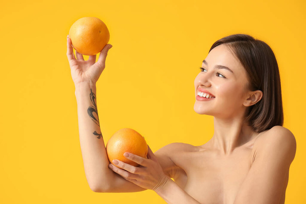 Naked young woman with grapefruits on color background. Vegan Day - 写真・画像
