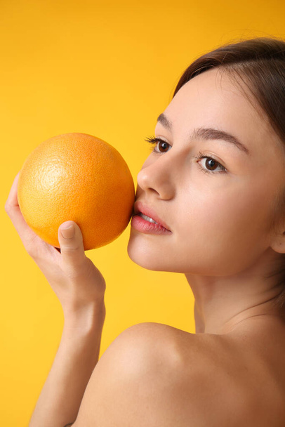 Naked young woman with grapefruit on color background. Vegan Day - Photo, Image