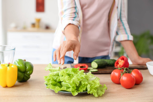 Mujer joven con verduras frescas en la mesa en la cocina - Foto, imagen