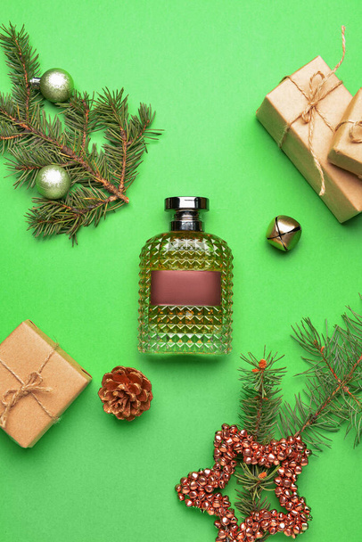 Perfume bottle, fir tree branches and Christmas decor on color background - Photo, Image