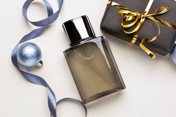 Parfüm palack, ajándék doboz és karácsonyi dekoráció világos háttér - Fotó, kép