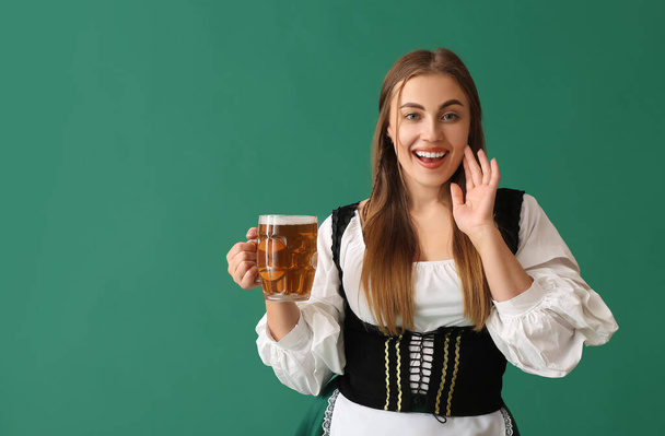 Schöne Oktoberfest-Kellnerin mit hellem Bier auf grünem Hintergrund - Foto, Bild
