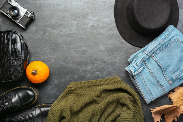 Κομψά ρούχα, αξεσουάρ, φωτογραφική μηχανή και φθινοπωρινή διακόσμηση σε σκούρο φόντο - Φωτογραφία, εικόνα