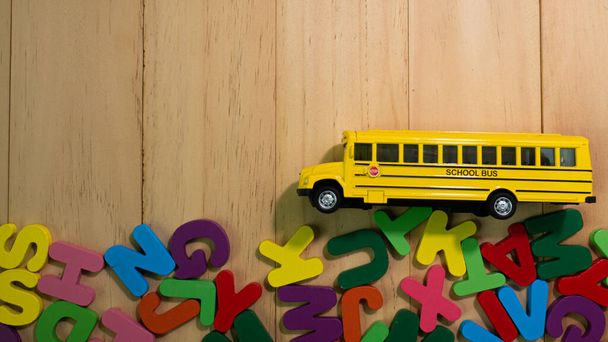 alfabeto in legno multi colore e scuolabus sul tavolo per l'istruzione o concetto di bambino - Foto, immagini