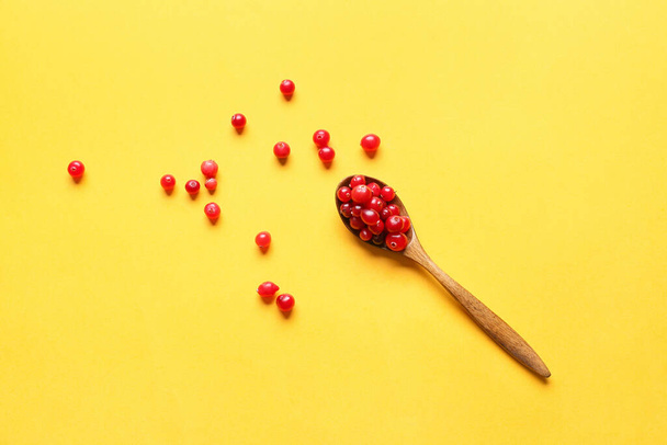 Κουτάλι με ώριμο lingonberry σε χρώμα φόντο - Φωτογραφία, εικόνα