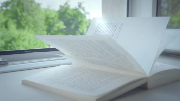 Libro abierto se encuentra en el alféizar de la ventana, el rayo de sol brilla en las páginas - Imágenes, Vídeo
