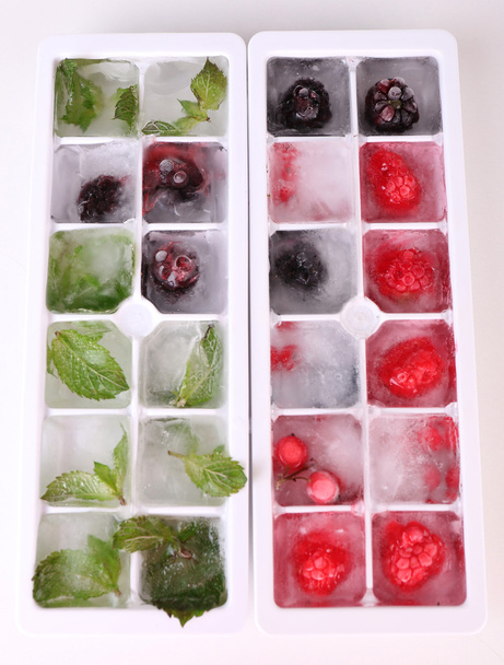 Ice cubes with forest berries, mint leaves in ice tray isolated on white - Foto, Imagem
