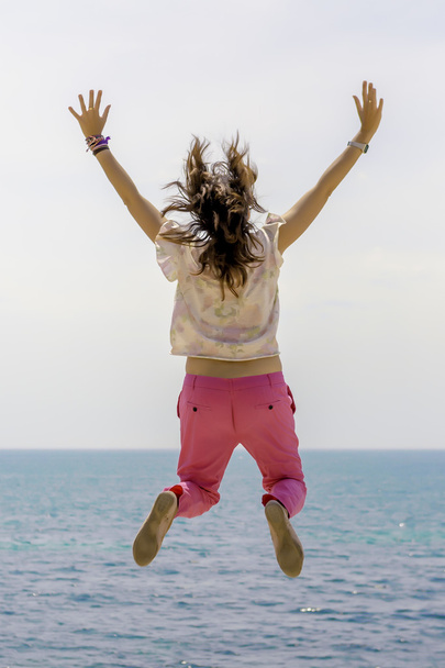 Молода жінка стрибає біля моря
 - Фото, зображення