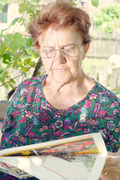 Elderly woman reading newspaper - Foto, afbeelding