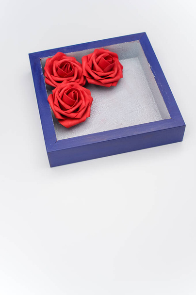 a blue wooden box with three red roses on a white background with text space - Photo, image