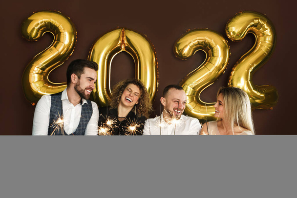 Group of beautiful well dressed party people celebrating 2022 New Year with burning sparklers - Fotoğraf, Görsel