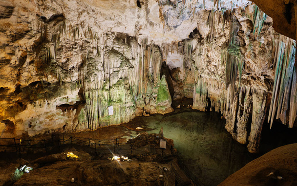 Ancient cave in north Sardinia with internal lake, reflections, stalactites and stalagmites - Photo, Image