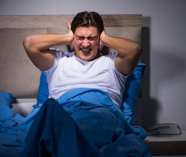 Junger Mann kämpft mit Lärm im Bett - Foto, Bild