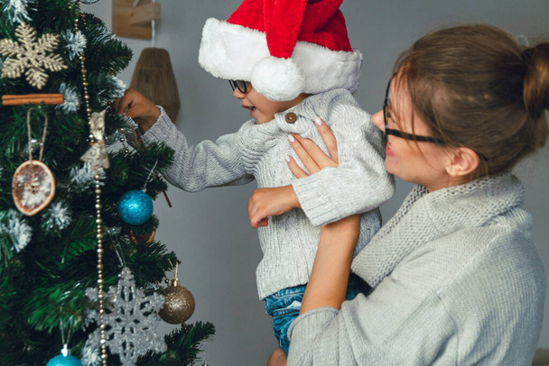 Mom and her child decorate the christmas tree together - Foto, immagini