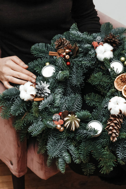 Woman is holding a handmade christmas wreath in her hands. - Photo, Image