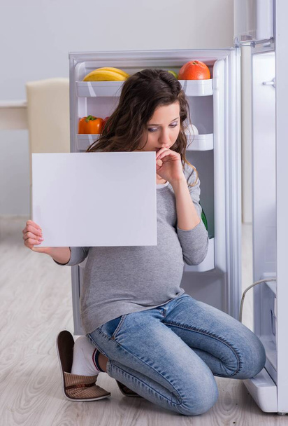 Femme enceinte près du réfrigérateur avec message vierge - Photo, image