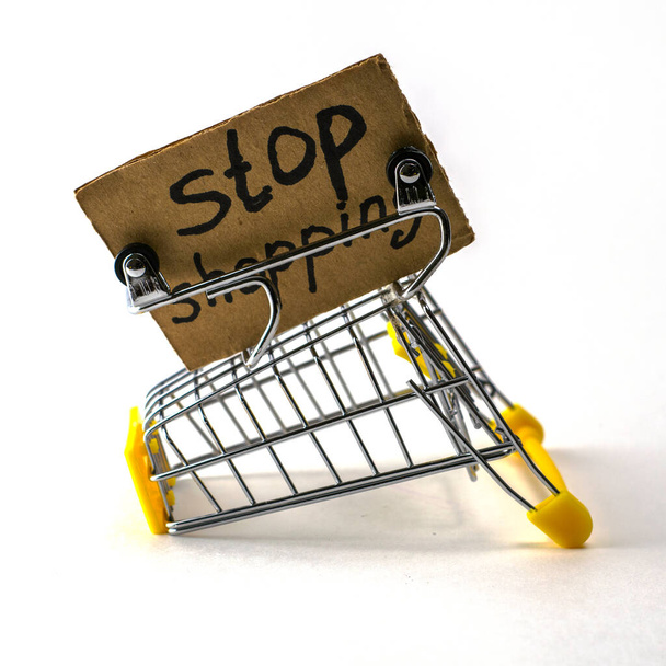 el concepto de negarse a comprar un consumo razonable es un carrito de compras invertido sobre un fondo blanco junto a un cartel que dice dejar de comprar. Foto de alta calidad - Foto, imagen