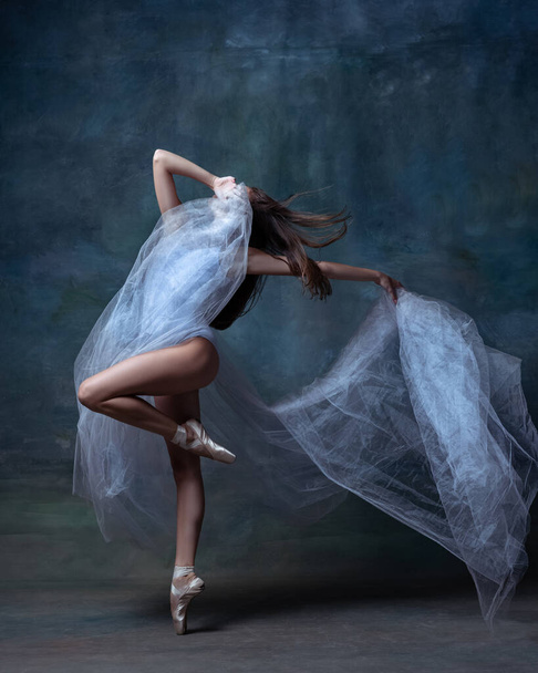 Portrait of young and flexible ballet dancer, ballerina dancing isolated on dark vintage studio background. Art, motion, action concept. - Valokuva, kuva