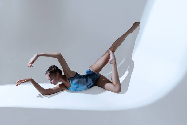 Young and graceful ballet dancer, ballerina dancing isolated on light studio background. Art, motion, action, flexibility, inspiration concept. - Φωτογραφία, εικόνα