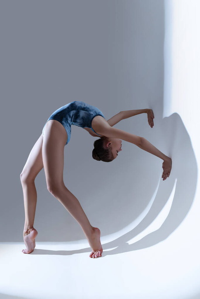 Young and graceful ballet dancer, ballerina dancing isolated on light studio background. Art, motion, action, flexibility, inspiration concept. - Fotoğraf, Görsel
