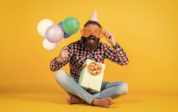 this is for me. man with gift box celebrating birthday. mature hipster with bright colorful balloons. Crazy funny guy. Relaxed happy birthday guy looks cheerful. bearded man feel the joy - Photo, Image