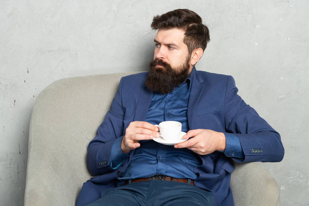 Relaxing professional man drink coffee sitting in rest armchair, coffee break - Фото, изображение
