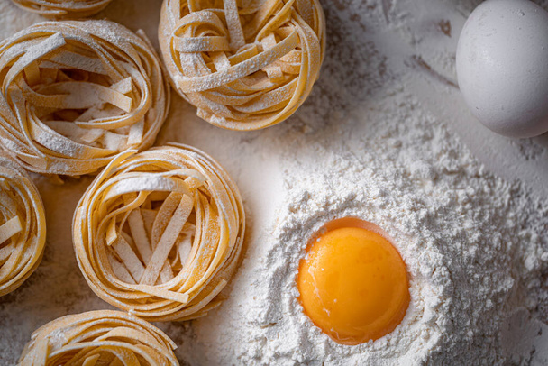 Homemade fettuccine pasta folded in the shape of a nest. Home cooking with ingredients for homemade traditional Italian fettuccine pasta. - 写真・画像