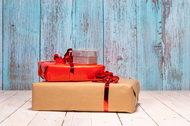 Σύνθεση με πολλά δώρα και χώρο για τις καλύτερες ευχές σας. Κόκκινα, καφέ και ασημένια κουτιά δώρου σε λευκό ξύλινο τραπέζι για τα Χριστούγεννα γεμάτα αγάπη. Χριστουγεννιάτικη ιδέα - Φωτογραφία, εικόνα
