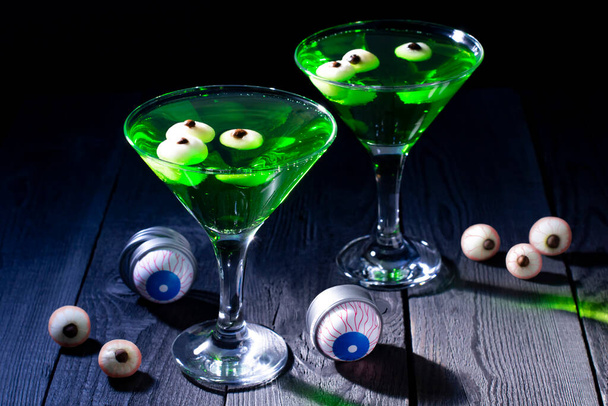 Brýle se zelenými halloweenskými koktejly a očními bulvami. Strašidelné nápoje s dekoracemi na Halloween party - Fotografie, Obrázek