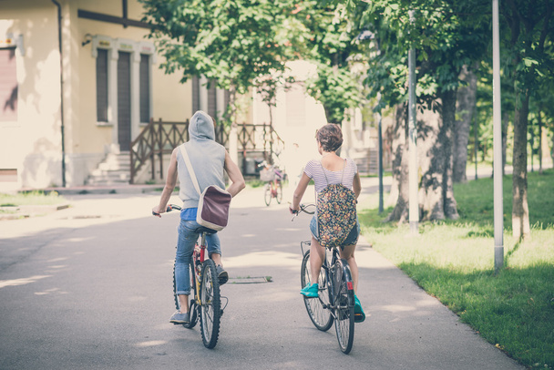 couple of friends young  man and woman riding bike - Foto, imagen