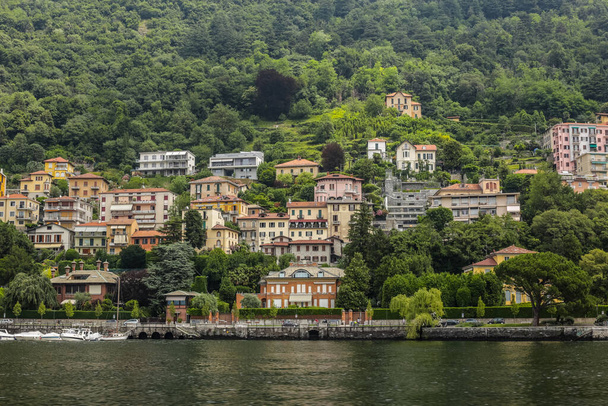 Como, Italia - 15 de junio de 2017: Vista de los turistas caminando por el lago con edificios coloridos tradicionales en el fondo - Foto, imagen